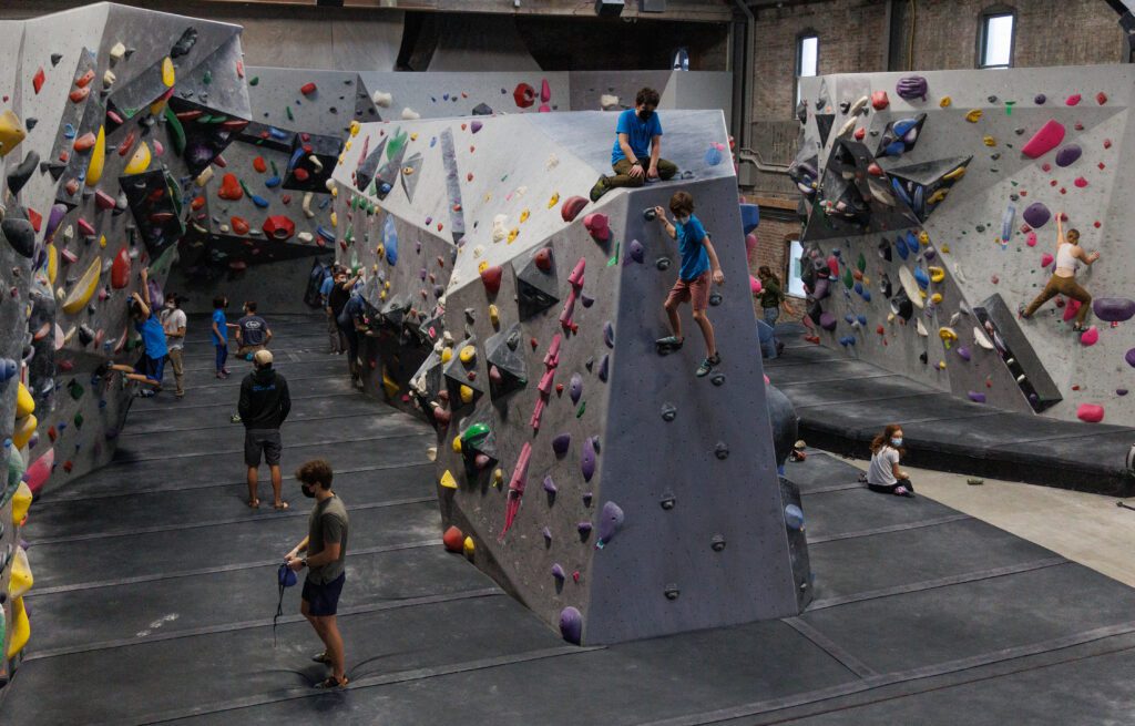 Madison McDaniel looks for her next hold as she and other climbers make their way up the rocks.