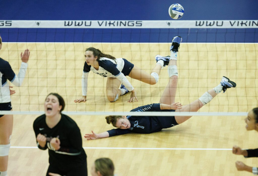 Central Washington University players celebrate a point as Western Washington University's Kasey Woodruff and Calley Heilborn are on the floor from a late dive.