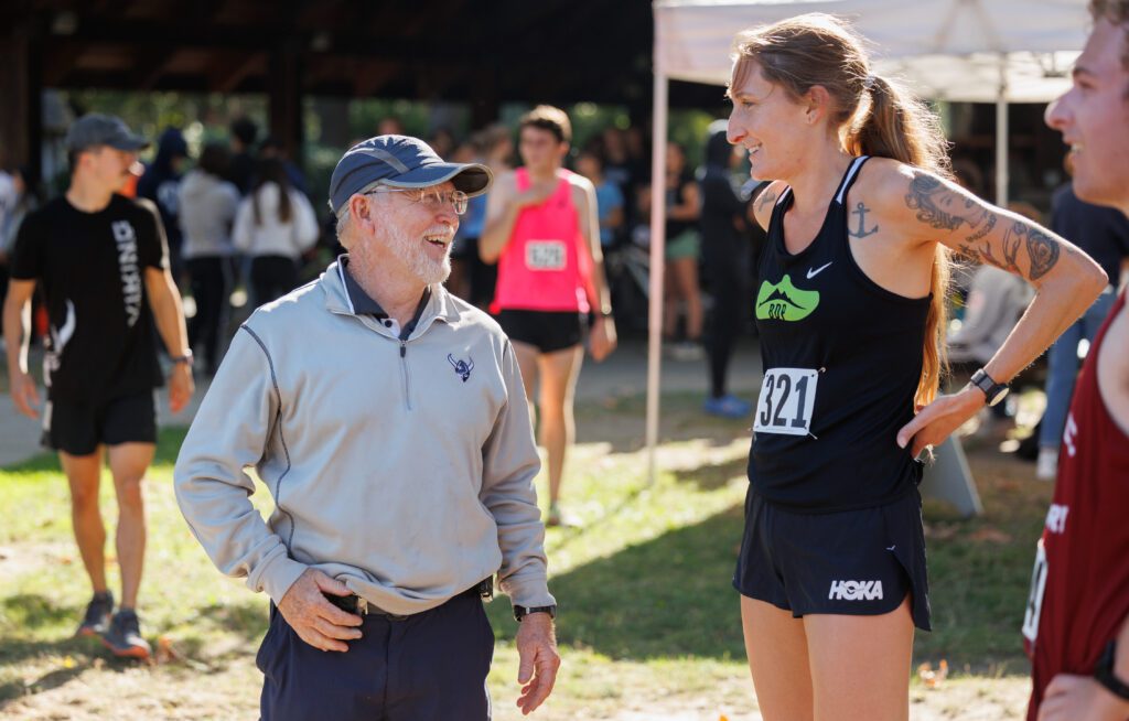 Western Washington University cross country head coach Pee Wee Halsell laughs with former Western runner Courtney Olsen underneath the bright sun.