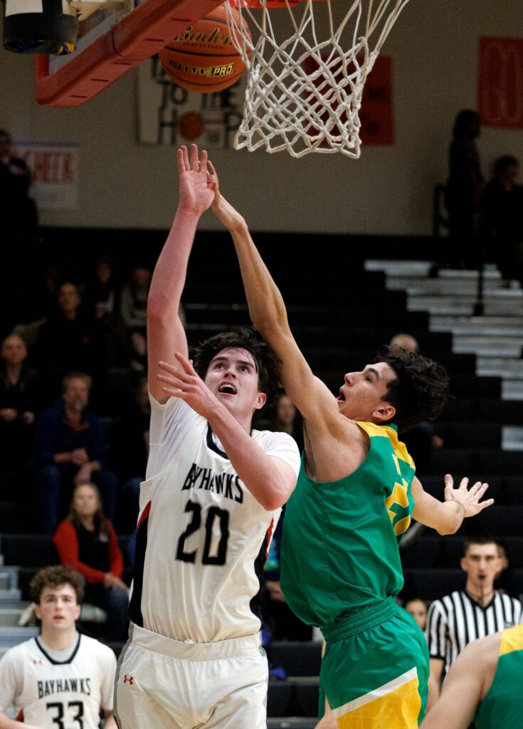 Bellingham’s Ian O'Roarty attempts to score from below the basket as a defender reaches over him in an attempt to block the shot.