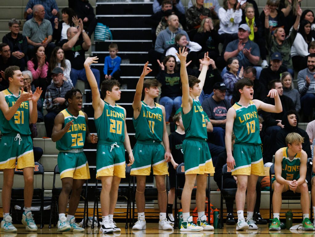 The Lynden bench players cheer and hold up trios of finger from the sidelines.