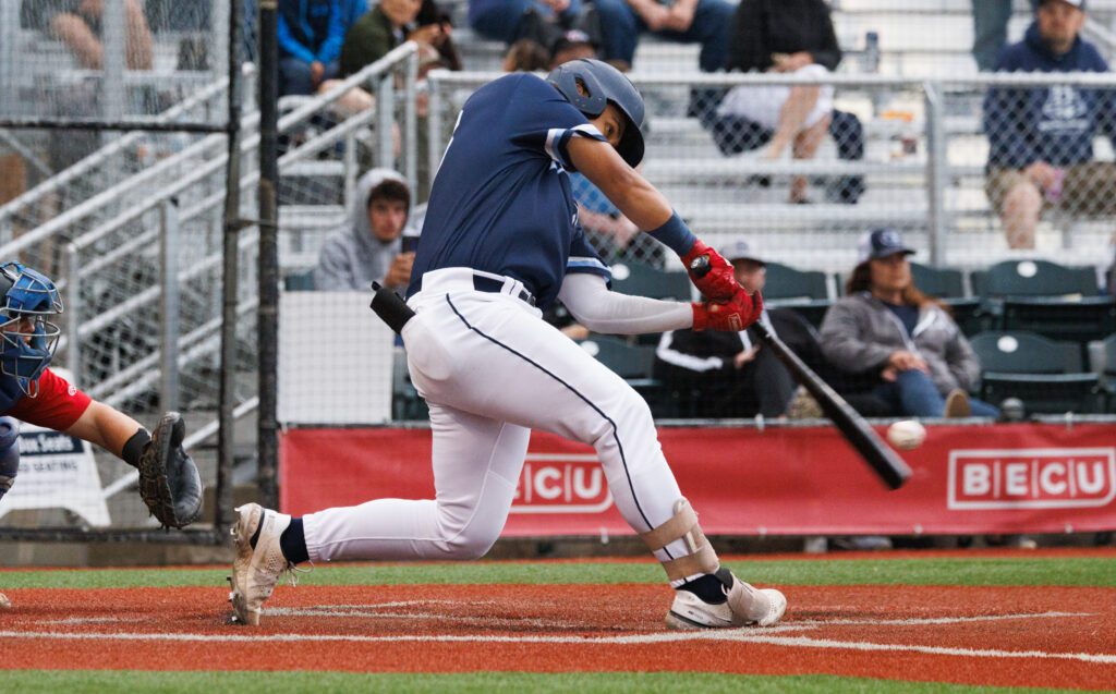 Chandler Tuupo drives in a run with the bat hitting the ball low to the ground.