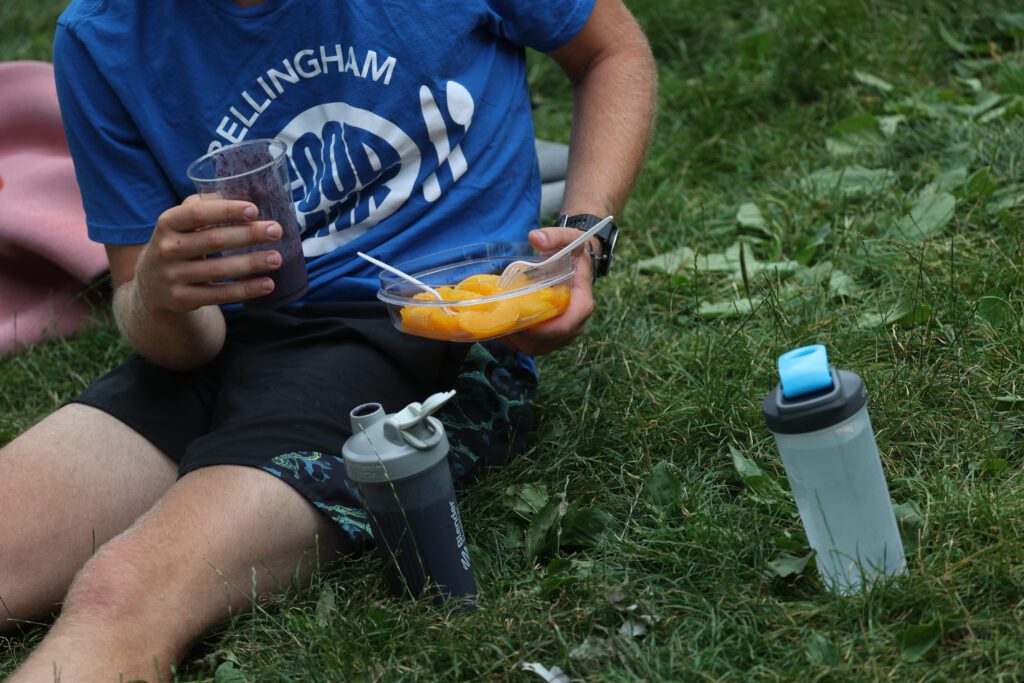 Ethan Hunger downs peaches, a shake and water on the grass.