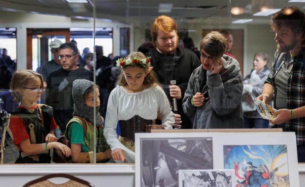 From left, Titus, Perrin and Selah Weston look over a table of free comics while dressed for the convention.