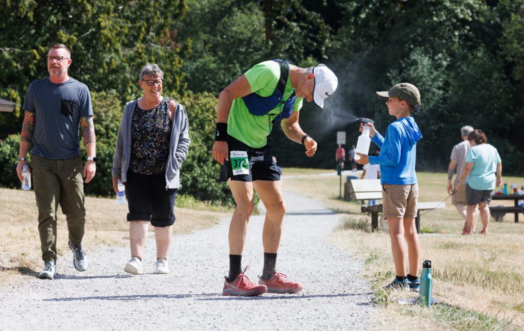 Runner Steve Ihnot, of Boulder, Co., gets a misting spray by volunteer Isaac West while on the run.