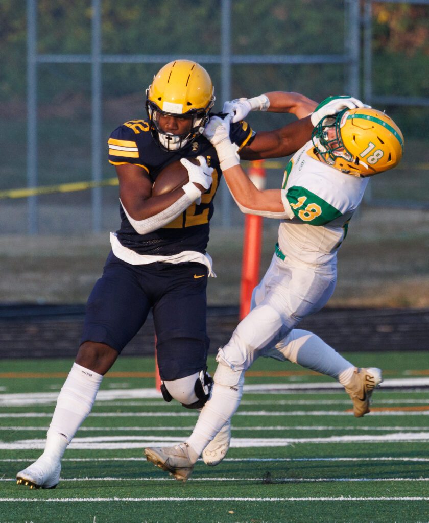 Isaiah Carlson pushes off Collin Anker with one hand while he holds onto the football with the other.