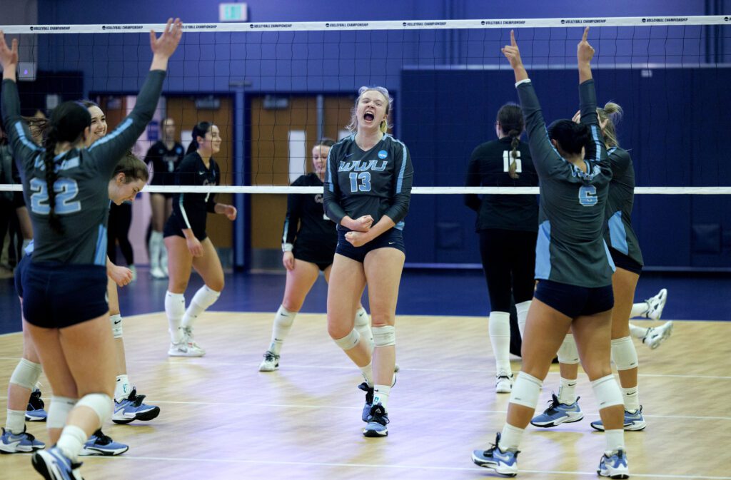 Western Washington University's Olivia Fairchild and her teammates celebrate with arms raised and happy cheers.