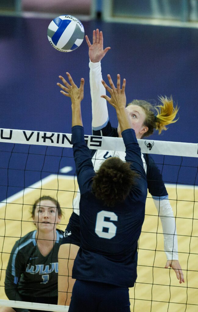 Western Washington University's Olivia Fairchild leaps to spike the ball over the net as a defender's hands are out of reach of the ball.