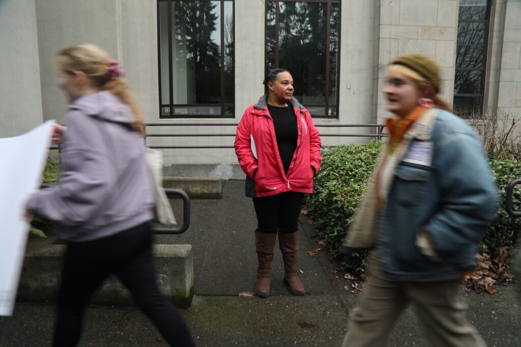 Bellingham City Council member Kristina Michele Martens watches protesters rush past her with signs.