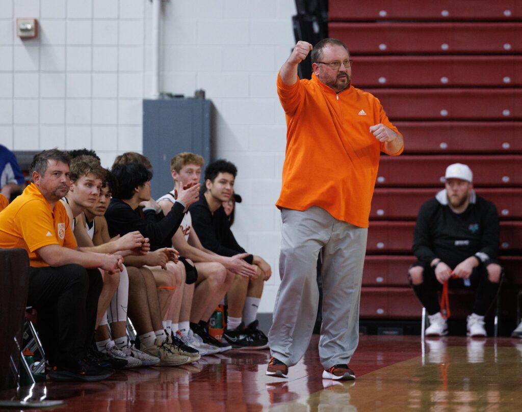 Blaine head coach Nate Sullivan pumps his fist in celebration as teammates from the benches clap.