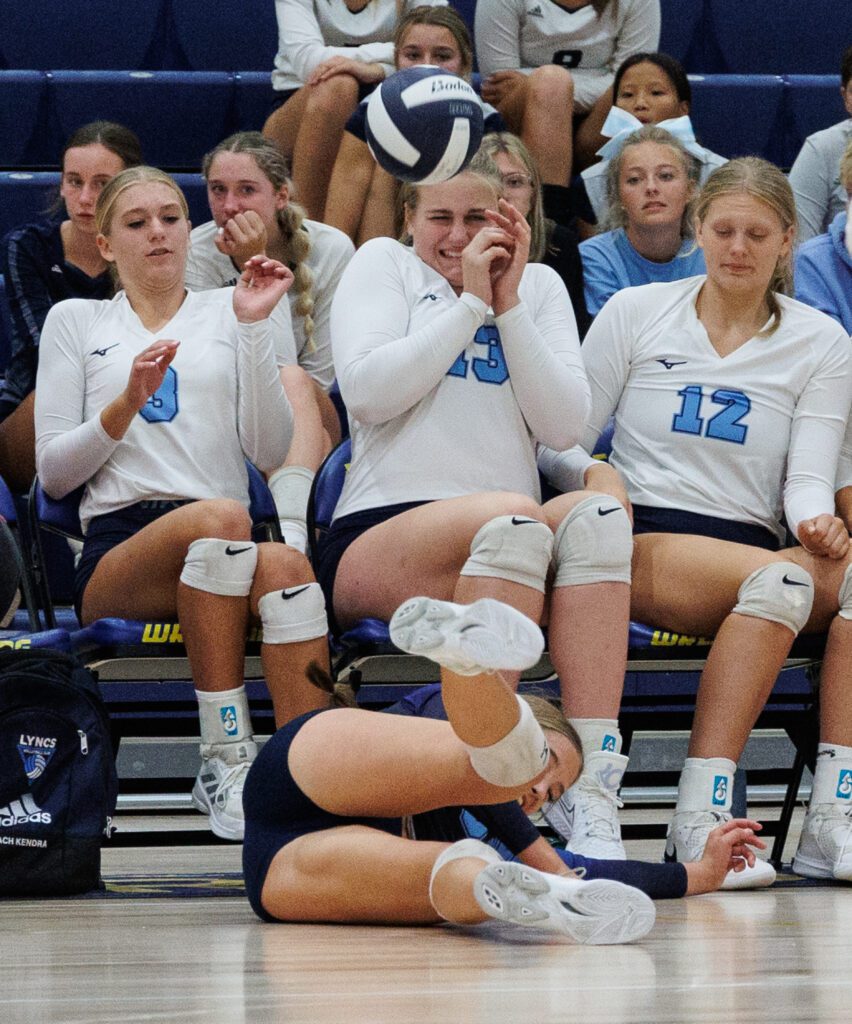 Lynden Christian's Sofia Rader crashes into the bench as the players seated brace for impact.