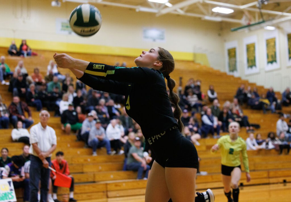 Lynden's Lucy White runs back toward the wall to keep the ball in play as spectators watch closely.