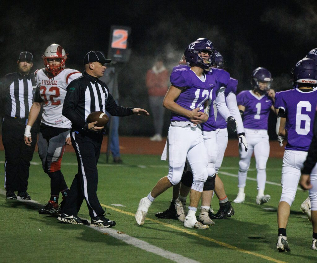 Holding his stomach, Nooksack Valley's quarterback Joey Brown walks away in pain.