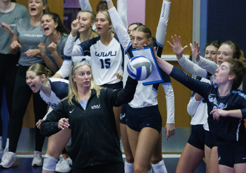 Head Coach Diane Flick-Williams uses her clipboard to stop the ball from reaching her team as some players brace for impact.