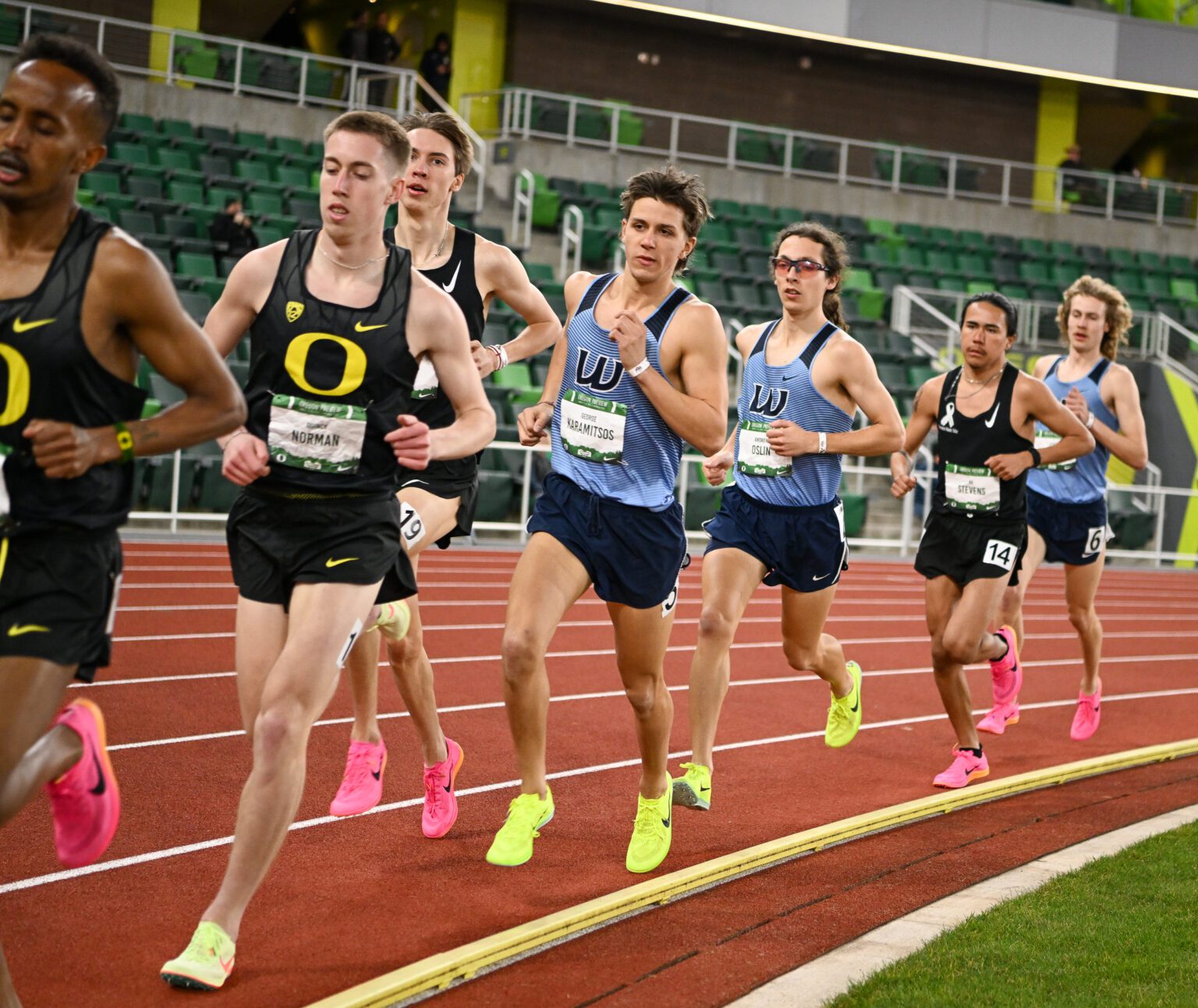 Runners sprint along the red track ahead of each other.