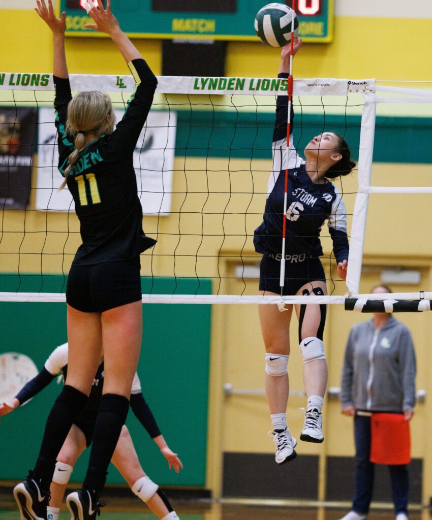 Squalicum’s Katie Nguyen leaps up for the spike as a defender does the same to block the shot.