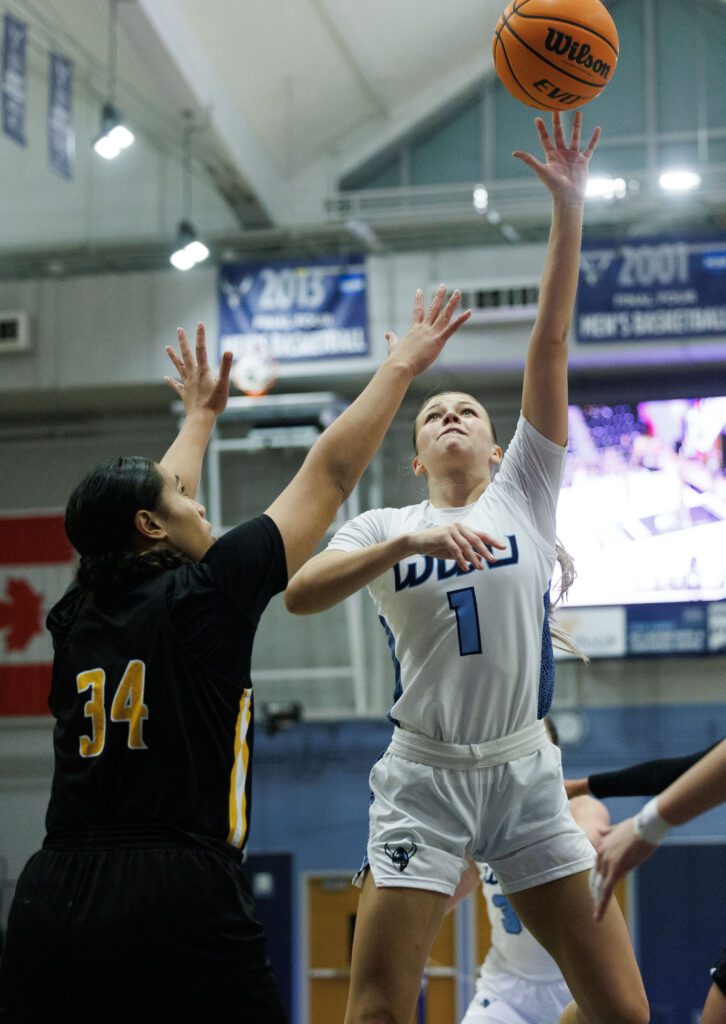 Western Washington University’s Avery Dykstra drives to the basket for a shot as a defender tries to reach for the ball.