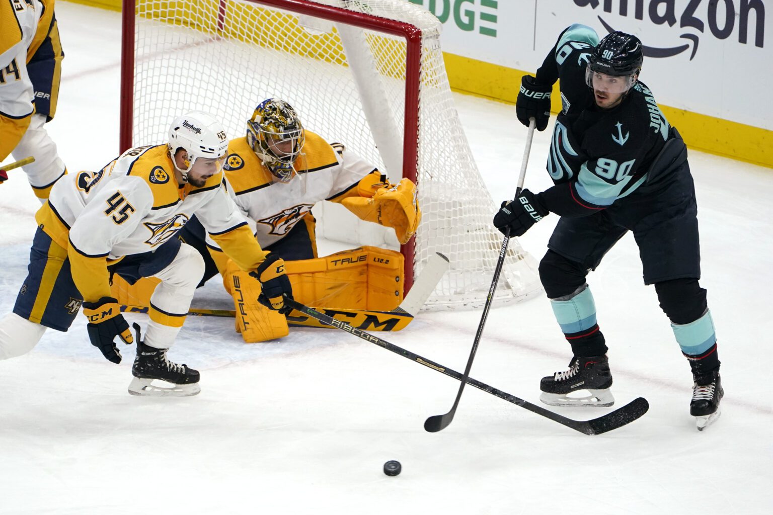 Seattle Kraken's Marcus Johansson (90) passes in front of Nashville Predators goaltender Juuse Saros, center, and other players who are low on the ground blocking the shot.