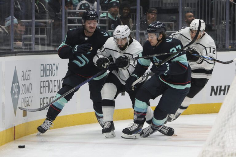 Los Angeles Kings center Phillip Danault (24) goes for the puck as Seattle Kraken defenseman Will Borgen and center Yanni Gourde try to defend their goal.