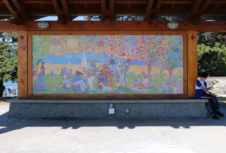 A boy sits by the colorful "The Porch" mural.