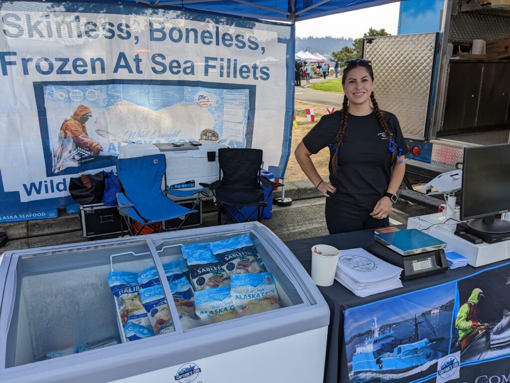 Amanda Andrew of Captain's Cod food truck at Bellingham SeaFeast with a freezer holding their frozen fillets.