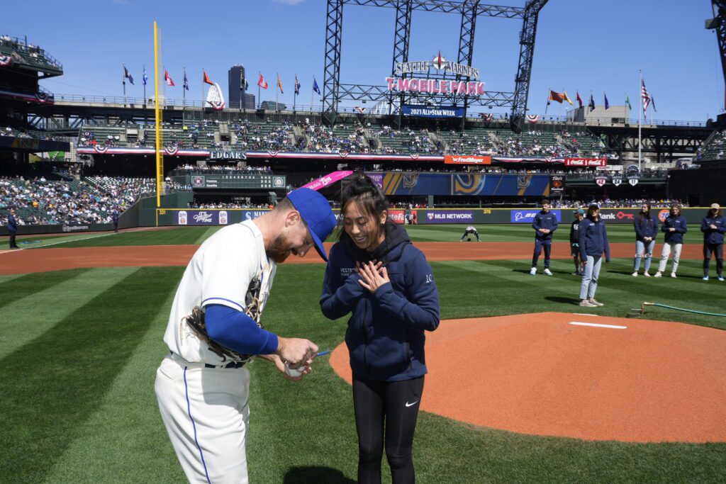 Iwami, with a wide smile, has her ball signed by Mariners infielder Donovan Walton.