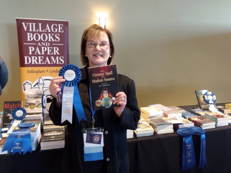 Author J.G. Schwartz with her novel "The Curious Spell of Madam Genova" and the blue ribbon she was awarded.