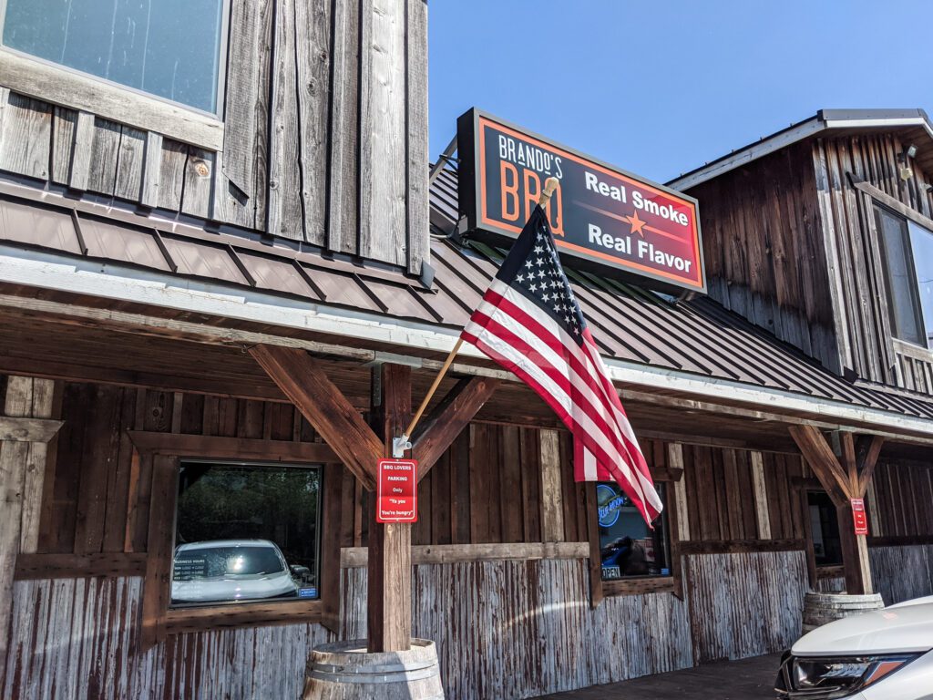 Located in what was previously a gun shop, the store front of Brando's has an American flag flying above a parking sign.