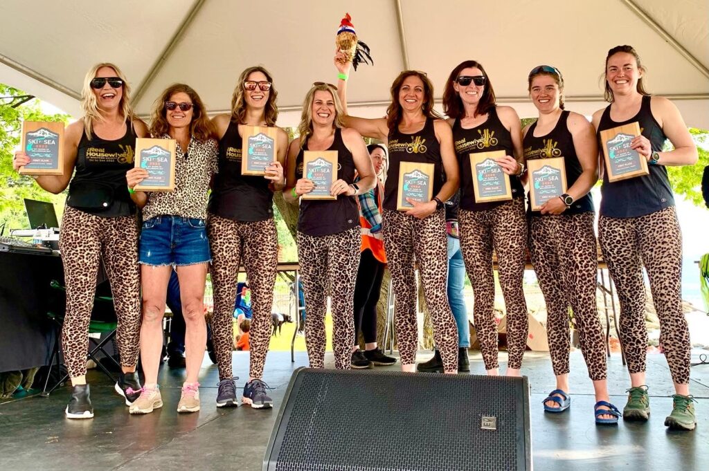 The Real Housewives of Whatcom County pose with their awards on stage while wearing matching leopard prints.