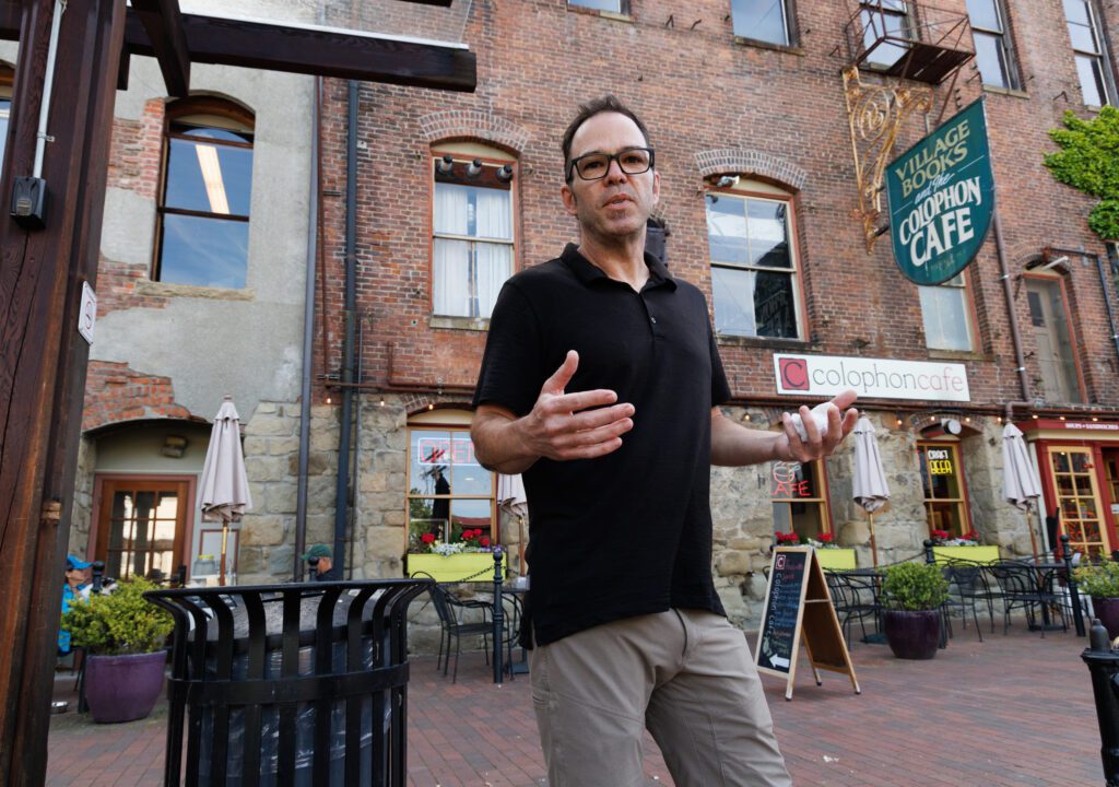 David Killian, owner of the Colophon Cafe, talks and gestures outside the Fairhaven neighborhood restaurant.