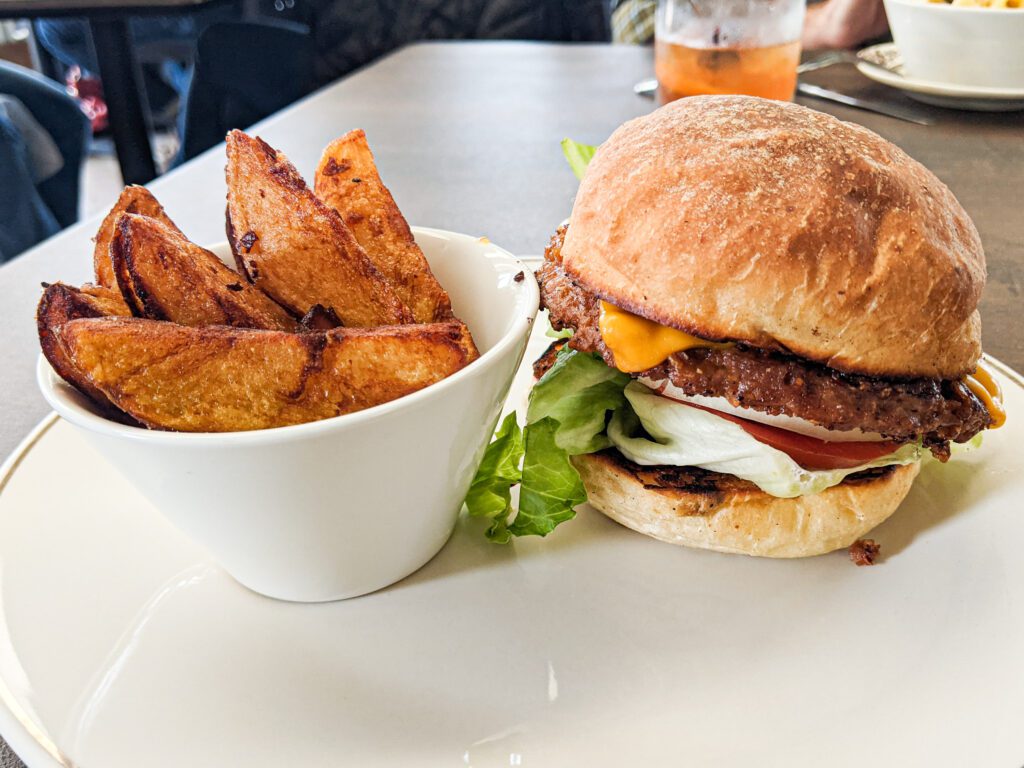 A vegan burger served with a side of roasted potato wedges.