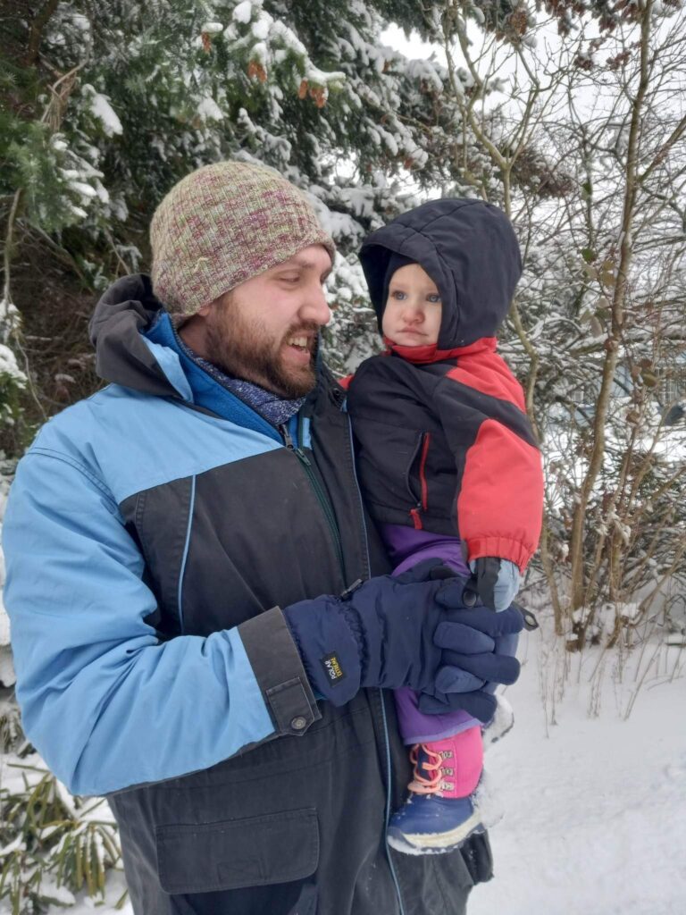 Ferndale Communications Officer Riley Sweeney poses with his child dressed in winter gear.