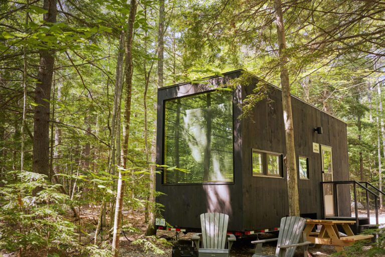 A Getaway cabin with wooden picnic tables and chairs.