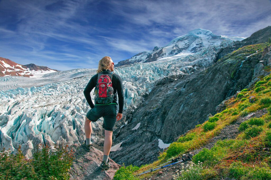 A hiker takes in the view of Heliotrope Ridge showing various drastic changes of scenery in one view.