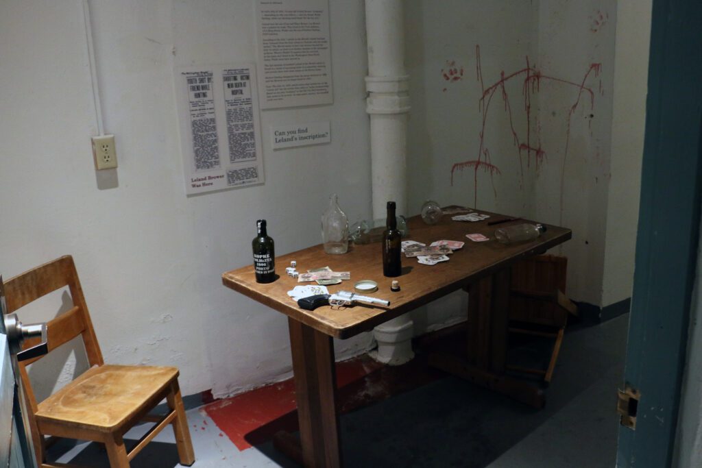 A vignette of a table with cars, alcohol and blood splatters on the walls tells the story of an argument breaking out over a card game,