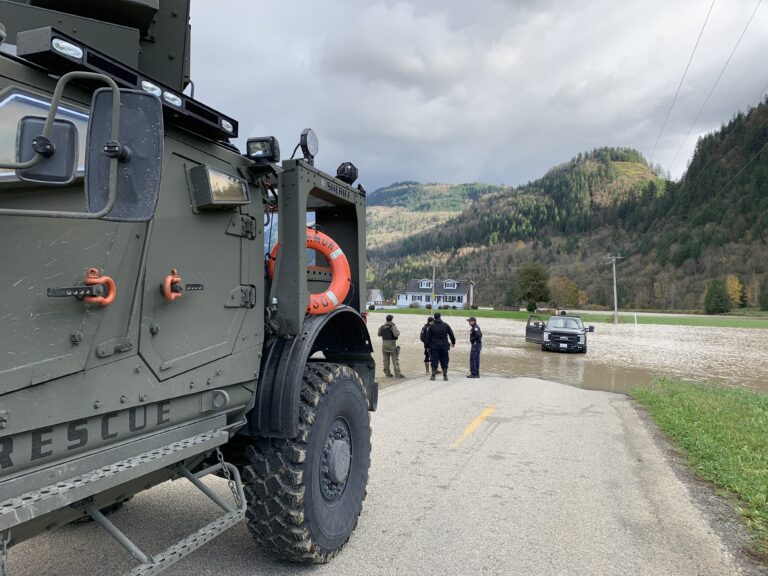 Mine-resistant vehicles (MRAPs) idling on a paved road.