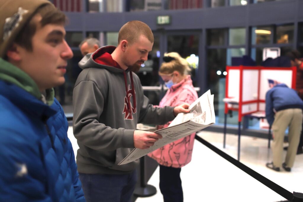 Colin Ney, left, and Remington Schroyer at the courthouse opens up a page of a newspaper.