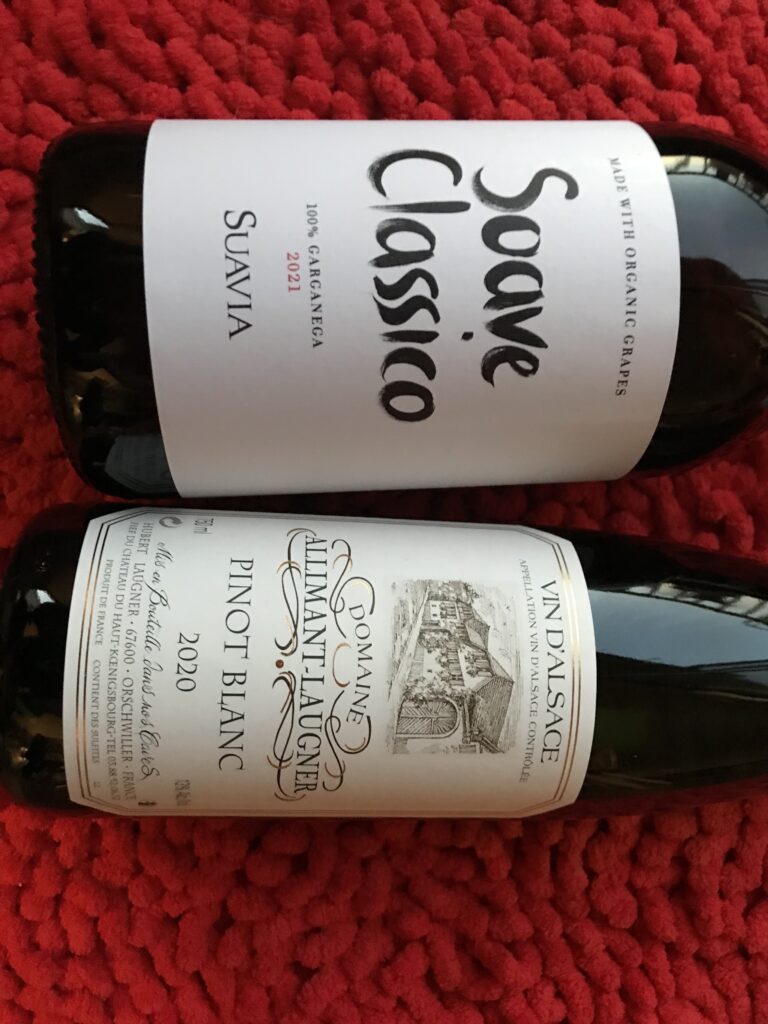 Two holiday wines placed on a red fabric.