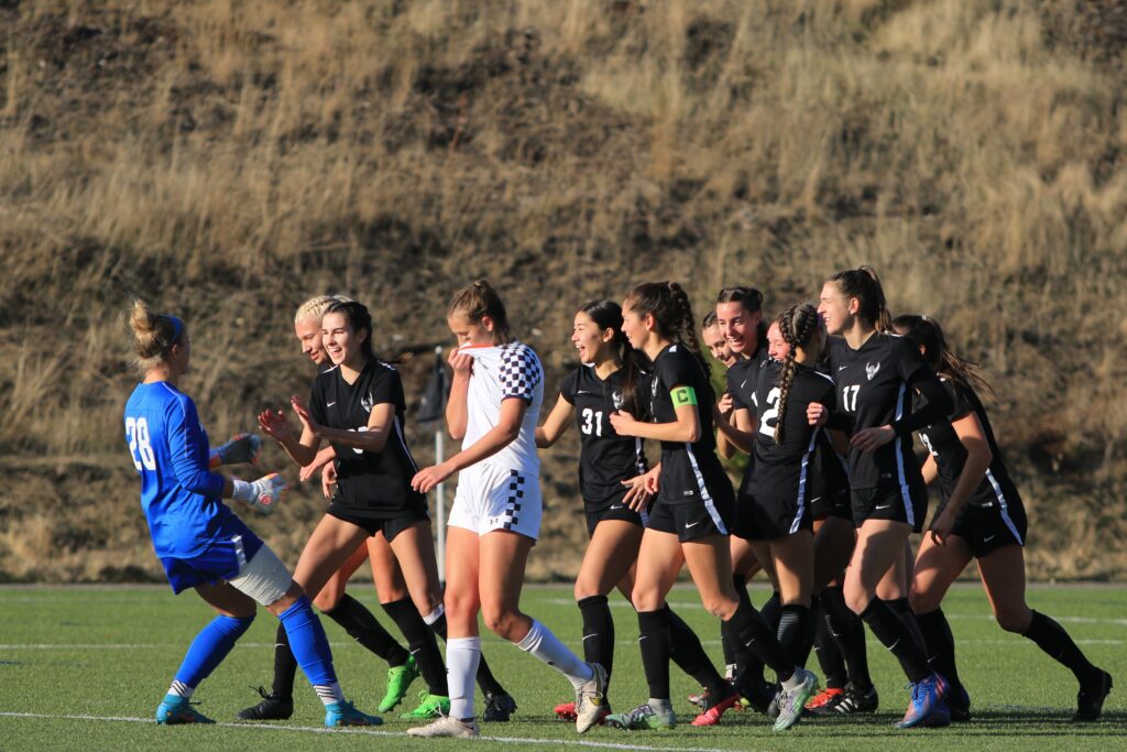 Fifth-year senior goalkeeper Claire Henninger, left, greets the rest of her team who are laughing and jogging along the grass.