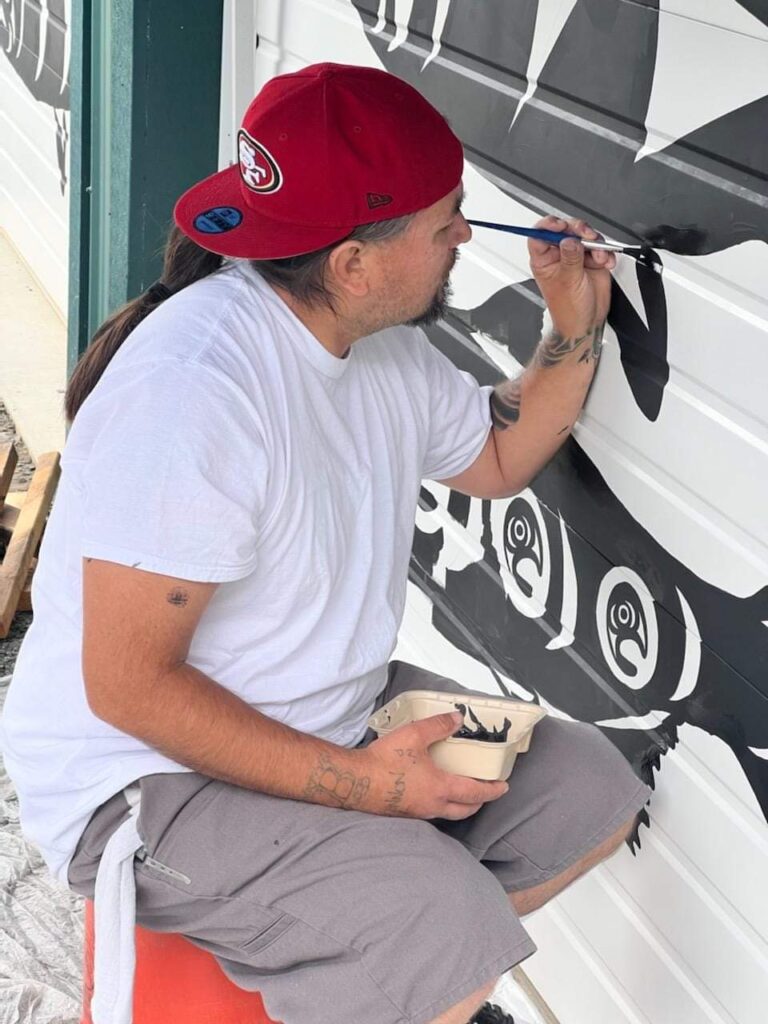 Painter and muralist Jason LaClair sits on a stool to paint fine details.