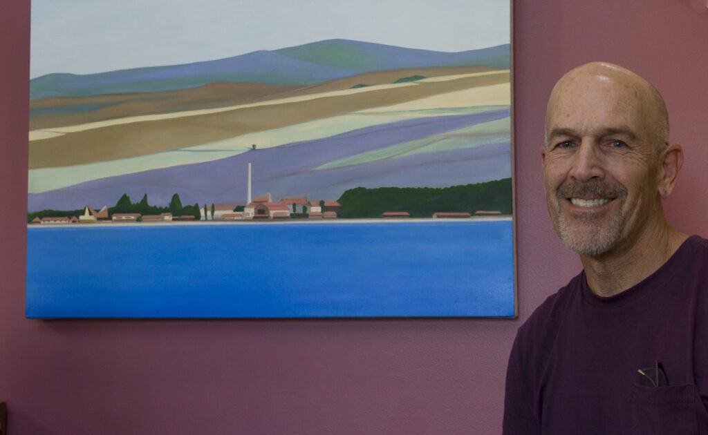 John Tolomei stands next to one of his paintings.