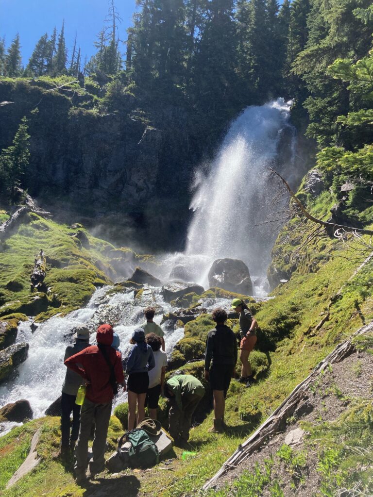 Outward Bound students admire a waterfall in Oregon's Three Sisters Wilderness as they take a break next to the rushing waters.