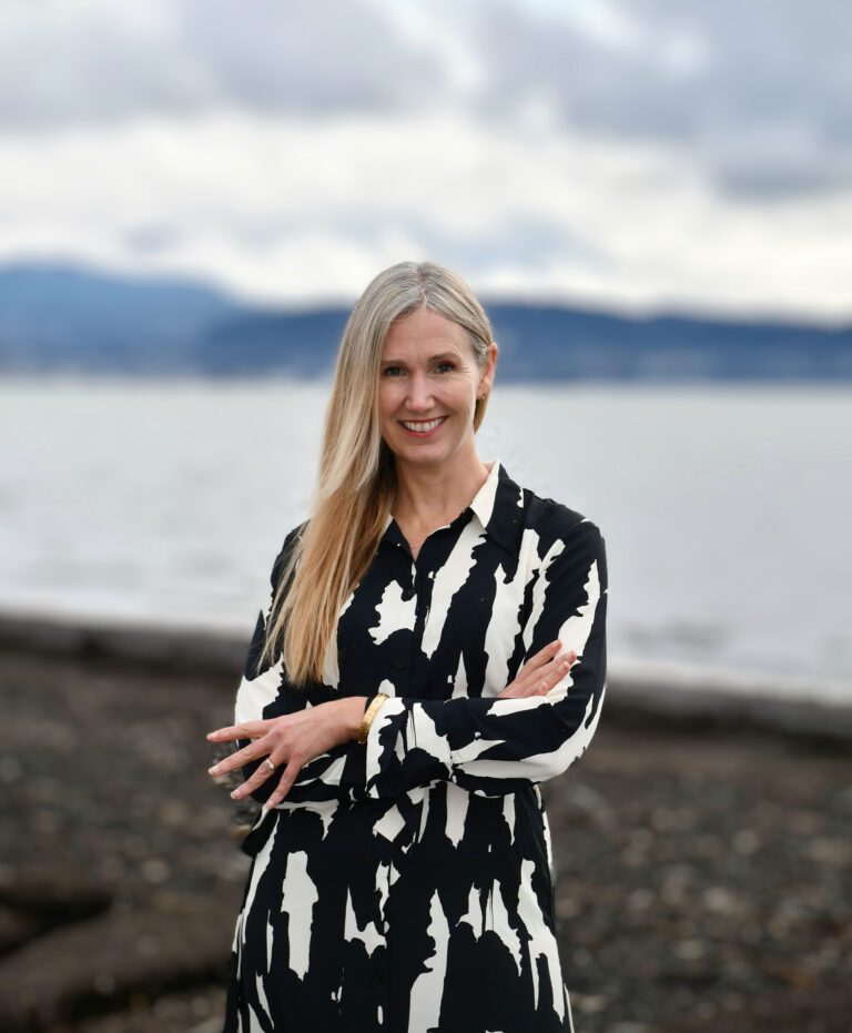 Kim Lund crosses her arms on the shores of a beach.