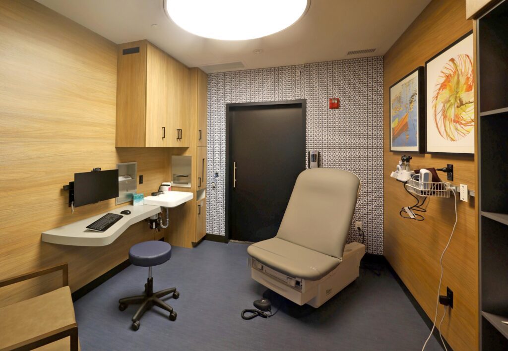 A Kinwell Medical Group exam suite has a seat for the patient as well as a stool next to a computer.