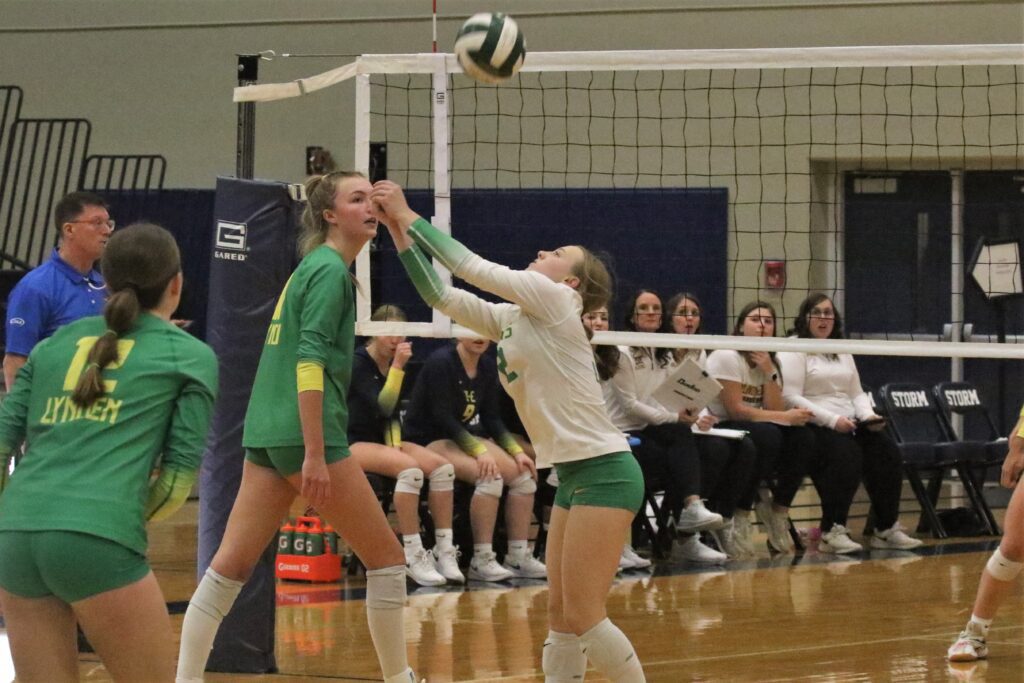 Lynden libero Mya VanderYacht (right) bumps a ball back into play as attendees watch.