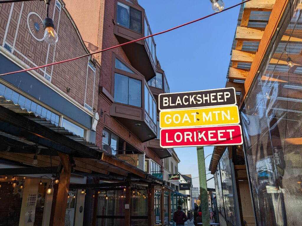 A sign near 215 W. Holly St. in downtown Bellingham with a sign in the same design as a street sign shows the restaurant names in different colors.