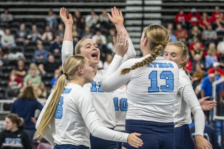 Lynden Christian's Reganne Arnold (11) throws her hands up in celebration as her teammates rush over to her.