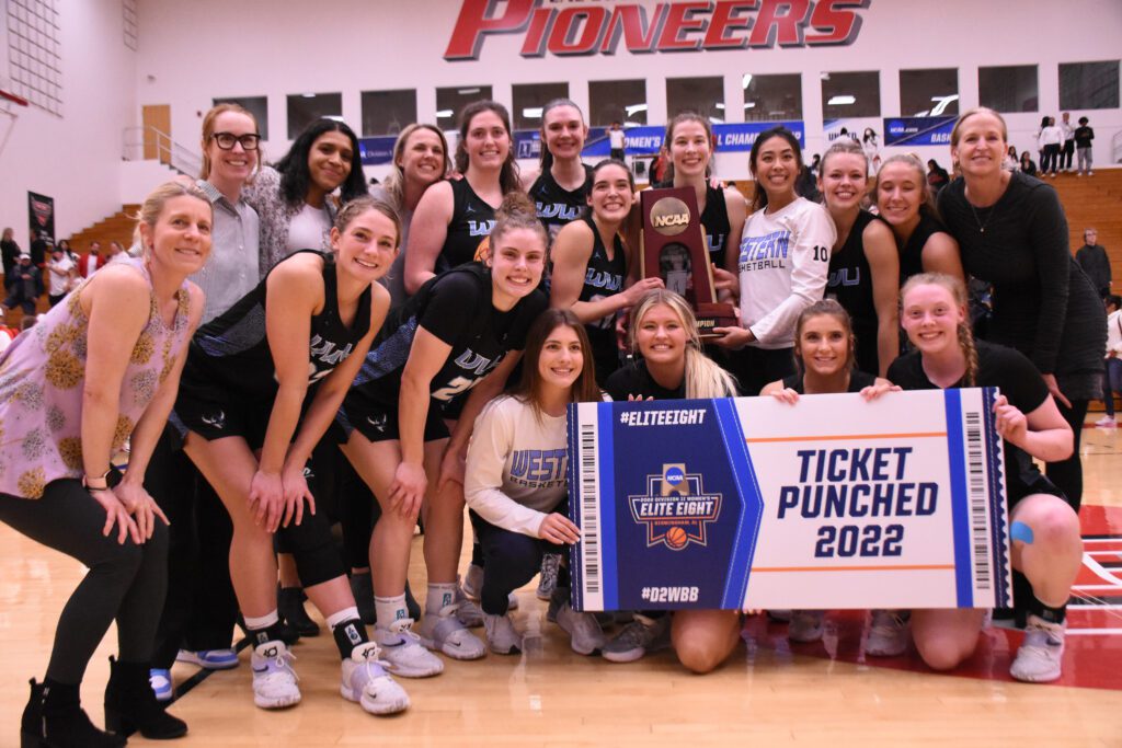 Western Washington University women's basketball players celebrate winning the NCAA Division II West Region title with a group photo with the trophy.