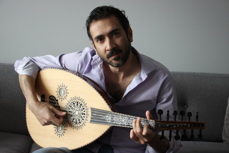 Originally from Syria, Morhaf Al Achkar plays his oud on his couch.