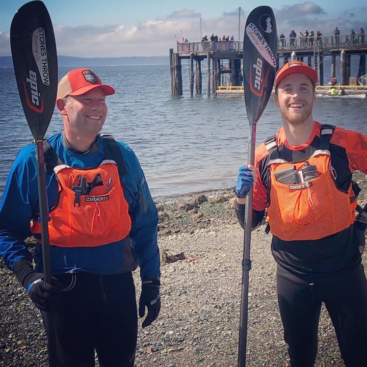 Bellingham paddlers Bart Maupin, left, and teammate Marc Furhmeister with wide smiles at the finish line while holding their paddles.